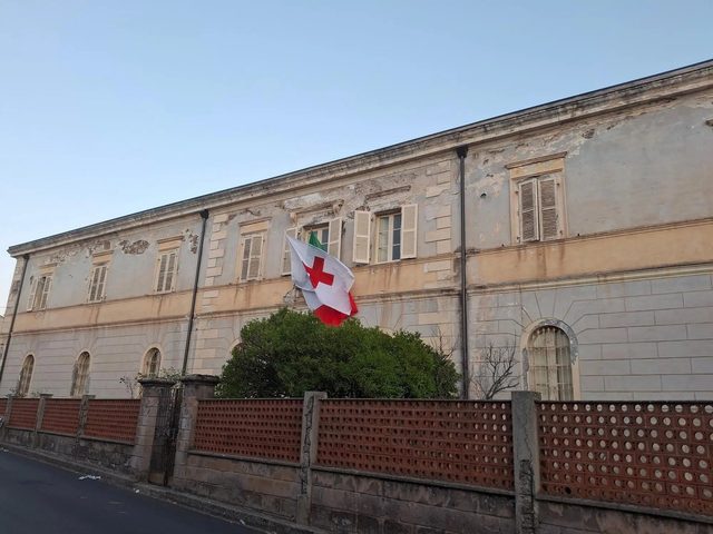 Facciata dell'ex Cottolengo, sede del Centro CRI di Ghilarza, con la bandiera della Croce Rossa